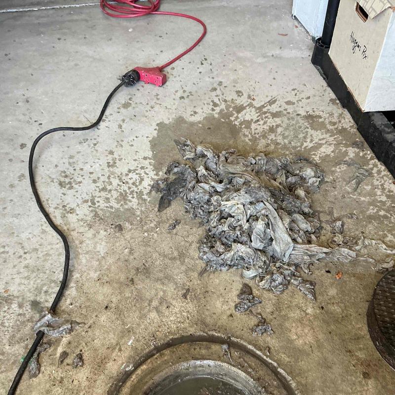 Drain cleanout with removed wipes pile on floor