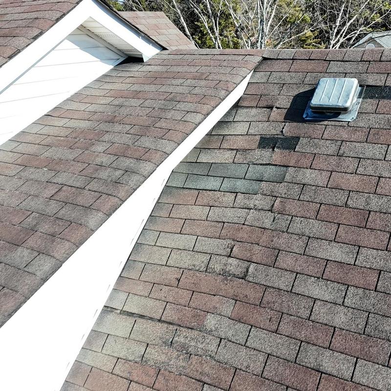 Asphalt shingle roof with visible damage and patch repairs