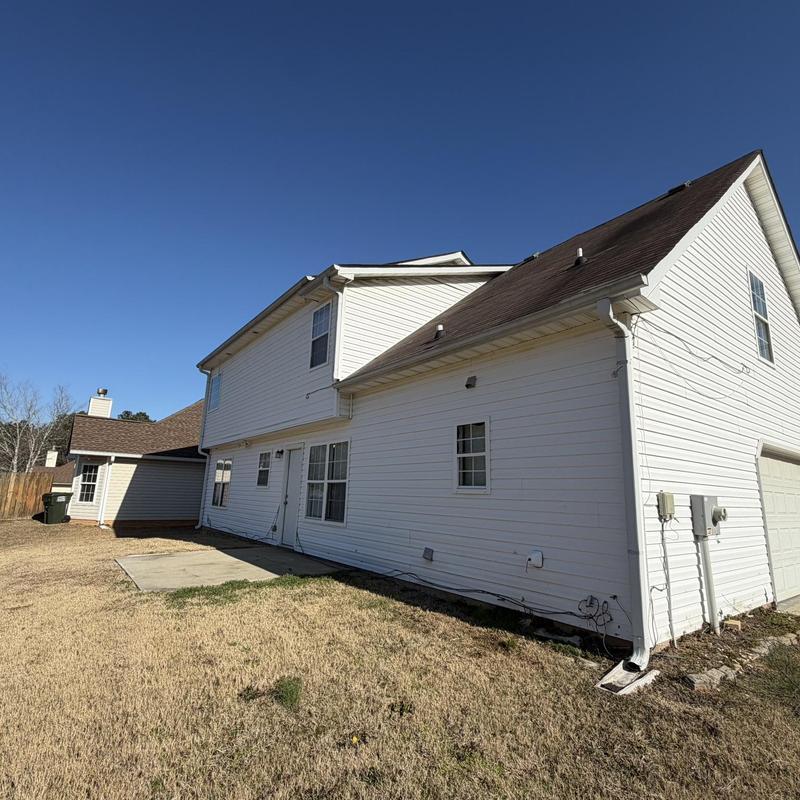 Roof shingles and gutter repair on white house exterior