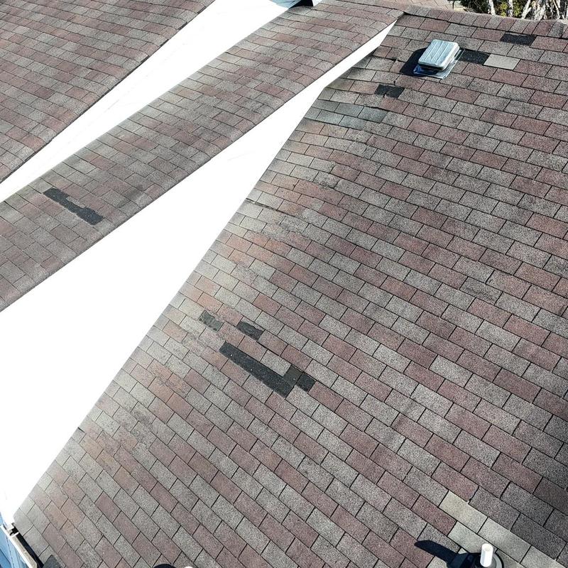 Roof shingles with missing and damaged sections near flashing