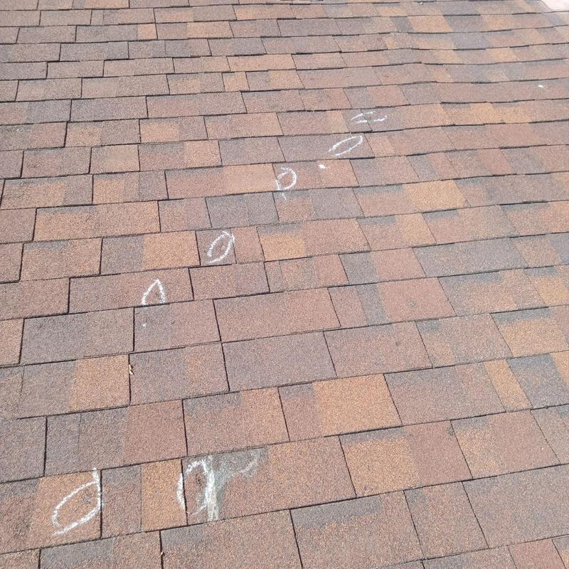 Asphalt shingle roof with hail damage marked in chalk Asphalt shingle roof with hail damage marked in chalk