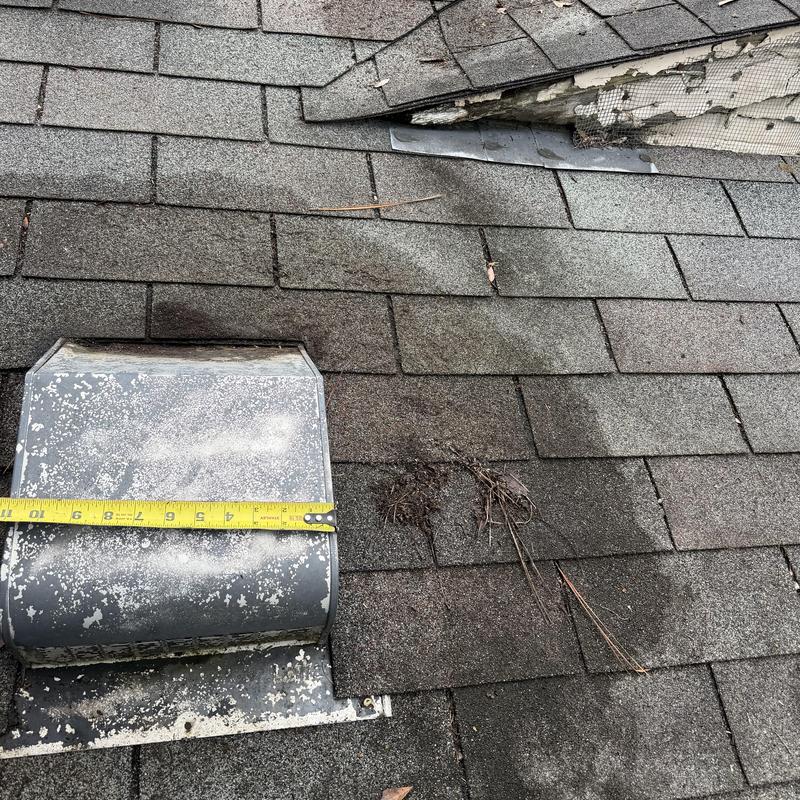 Roof shingles with damaged vent and tape measurement