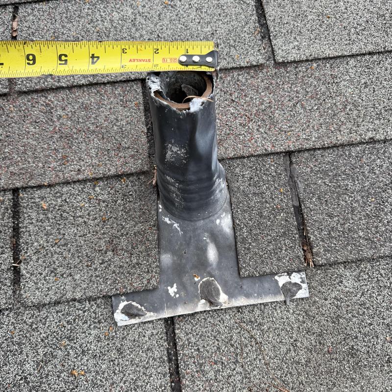 Roof pipe flashing with damaged seal and measuring tape