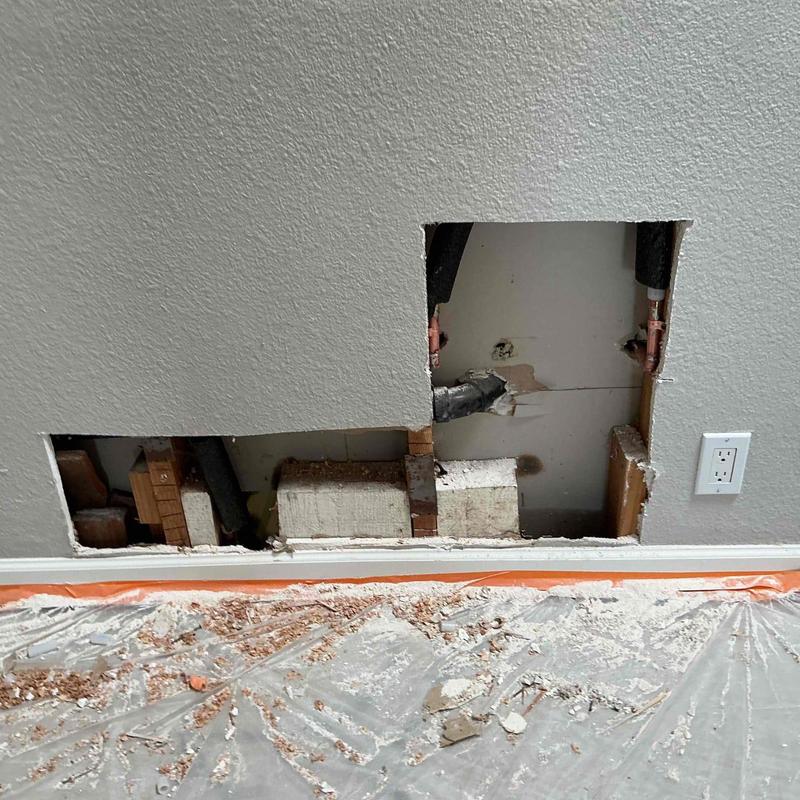 Copper plumbing pipes exposed behind drywall cutout
