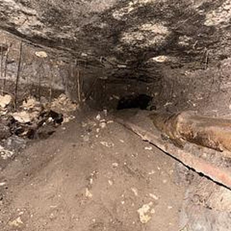Cast iron drain pipe under slab with excavation tunnel