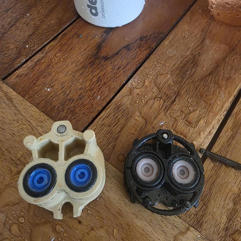 Shower cartridge parts with water droplets on wood table
