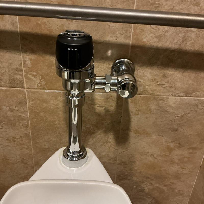 Battery powered flush valve on toilet in restroom stall