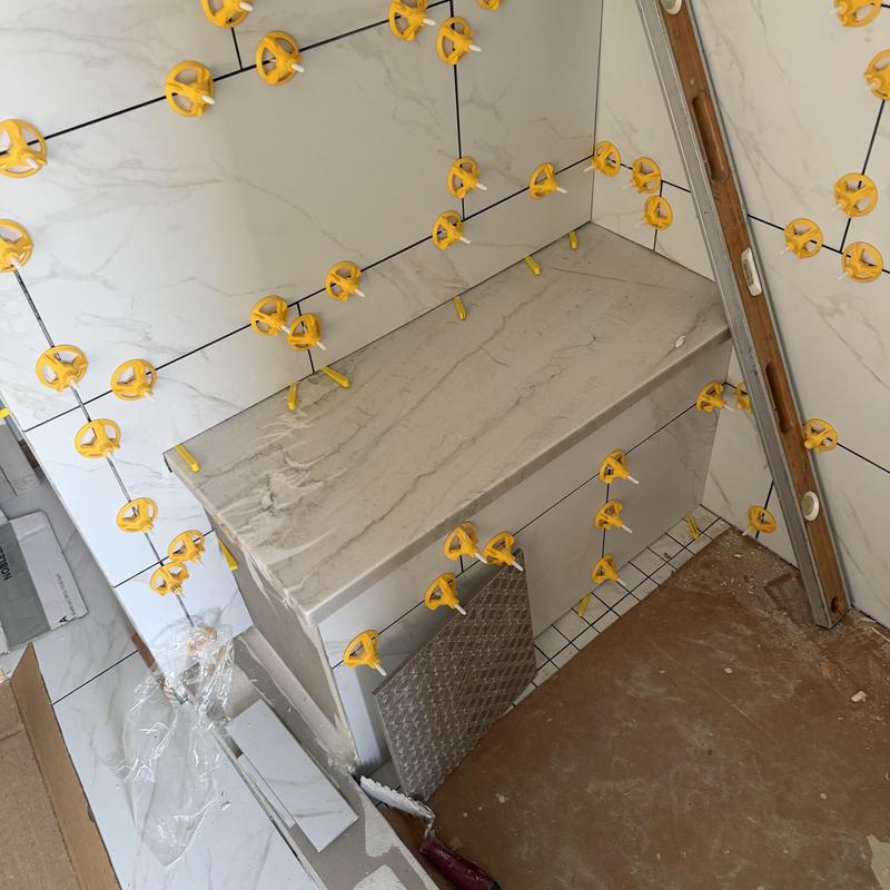 Granite countertop installation with tiled walls and spacers