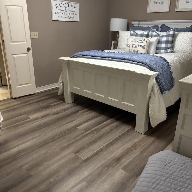 Vinyl flooring installation in bedroom with white bed