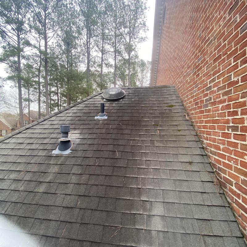 Asphalt shingle roof with vent pipes and moss buildup