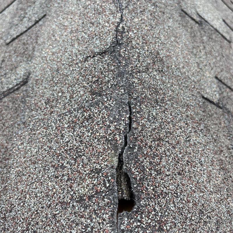 Roof shingle with crack and hole from hail damage