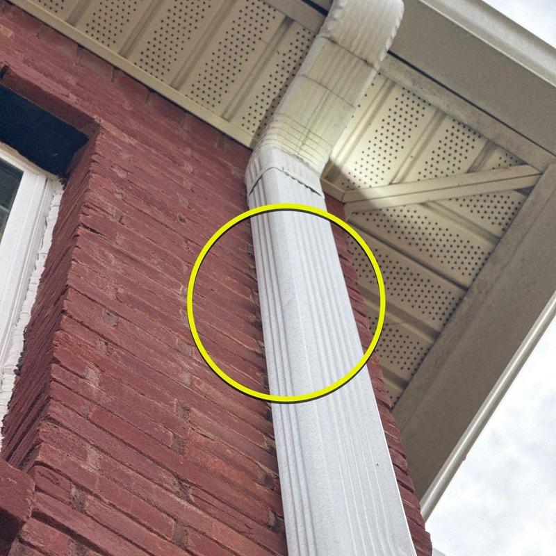 Downspout section on brick exterior near roofline