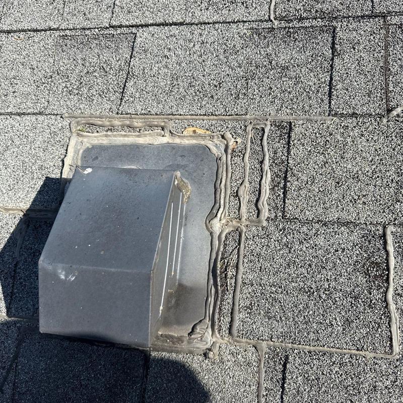 Metal roof vent with surrounding sealant on asphalt shingles