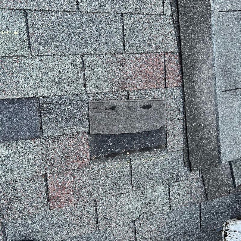 Roof shingles with hail damage and raised flashing edge