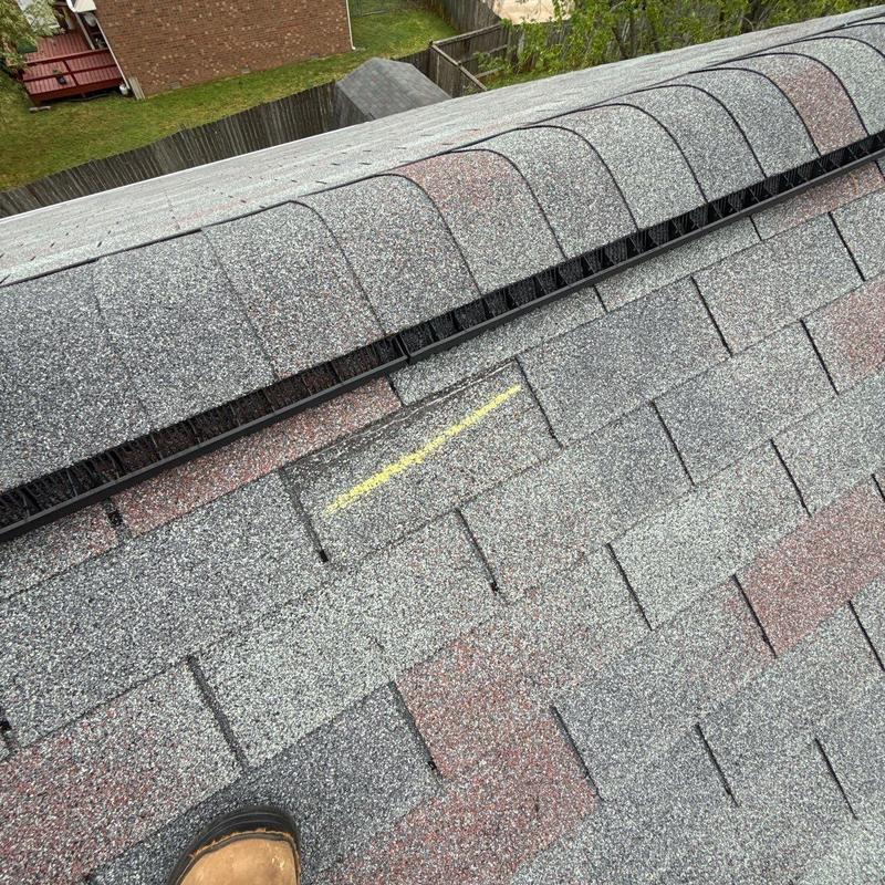 Asphalt roof shingles with marked hail damage near ridge cap