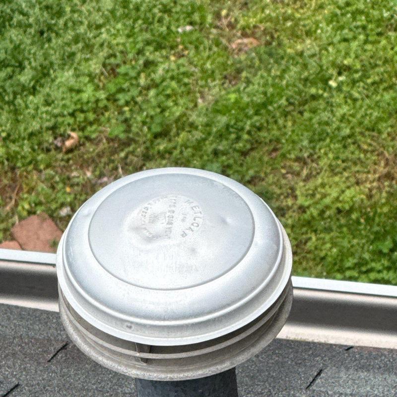 Roof vent cap with hail damage on shingle roof