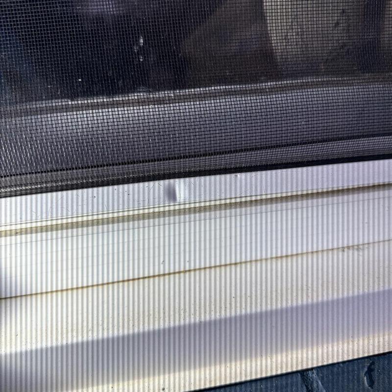 Window frame with dent behind screen mesh