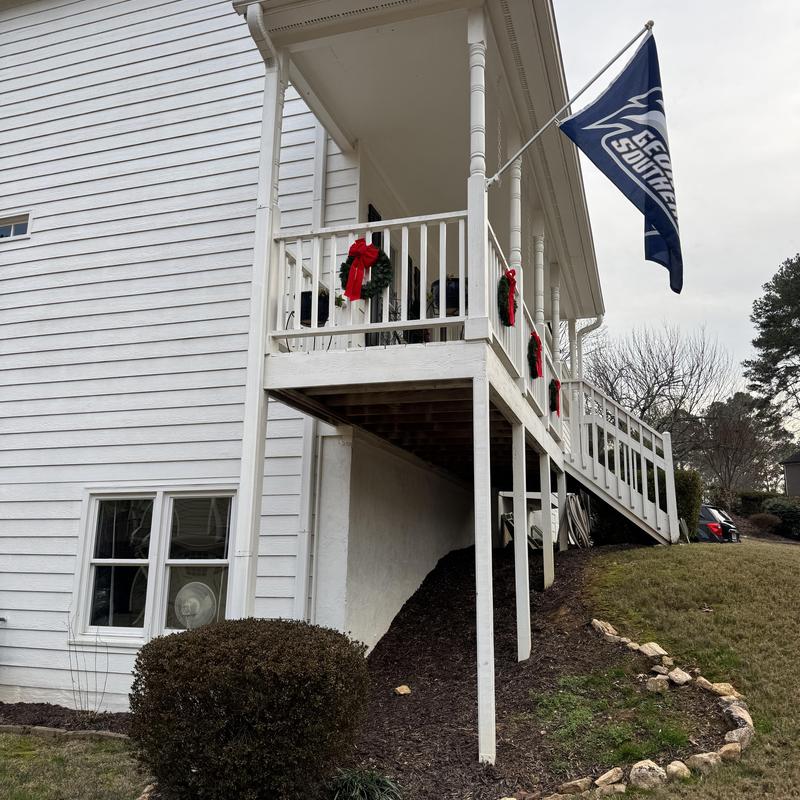 Front porch framing posts and white railings with wreaths