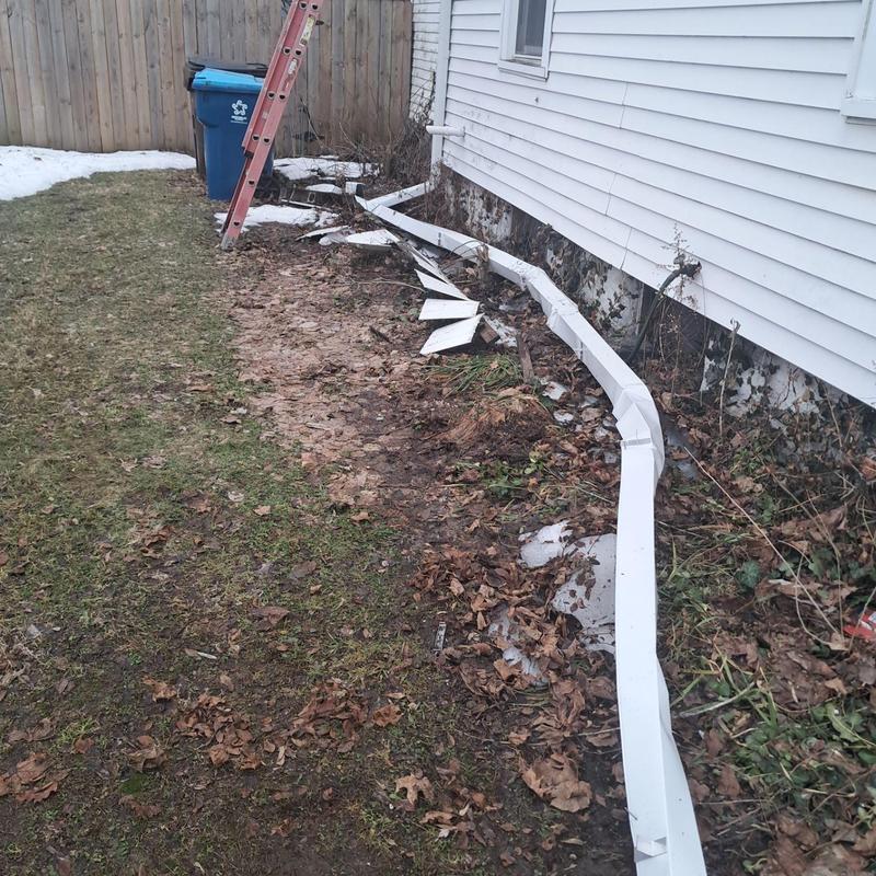 Damaged white gutter detached from house siding Damaged white gutter detached from house siding