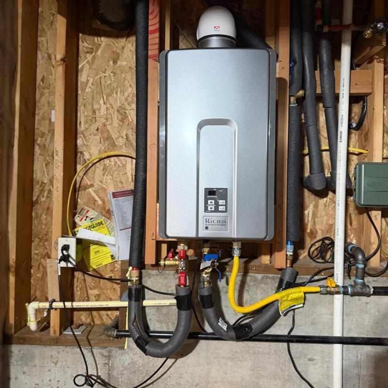 Tankless water heater with piping in basement wall