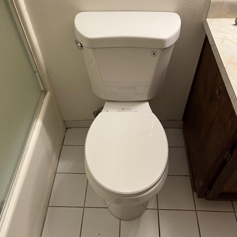 Toilet with closed lid installed in bathroom corner