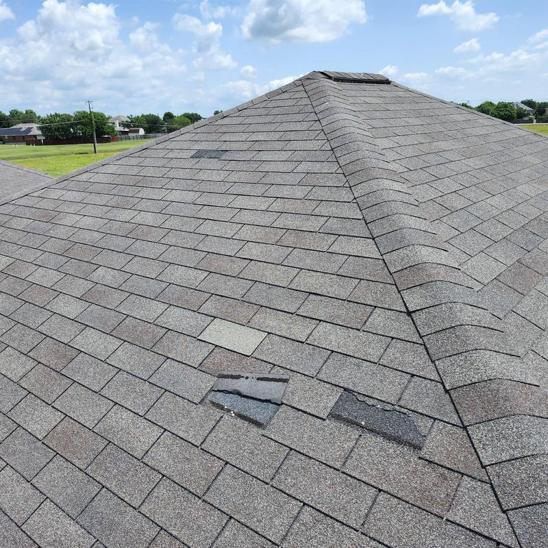 Roof shingles missing and damaged on residential roof