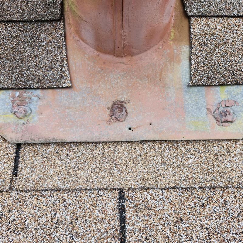 Plumbing boot flashing with caulked exposed fasteners on roof