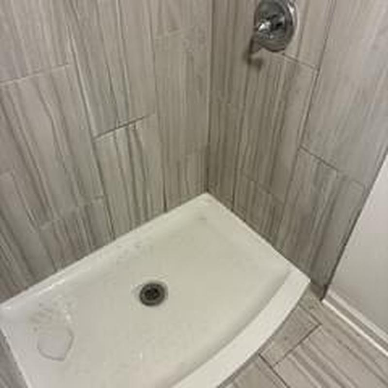 Shower drain and tiled shower stall in bathroom