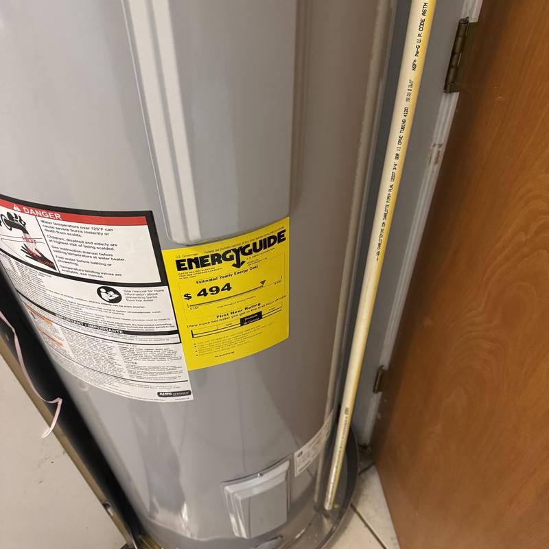 Electric water heater with EnergyGuide label near door