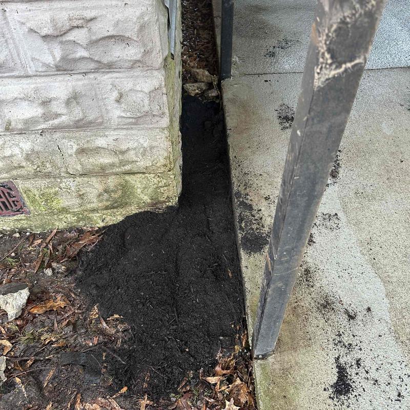 Soil backfill along foundation and concrete walkway Soil backfill along foundation and concrete walkway