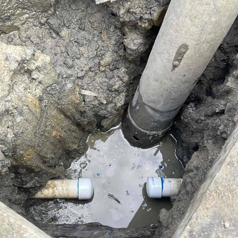 PVC plumbing pipe sections in excavated muddy pit PVC plumbing pipe sections in excavated muddy pit