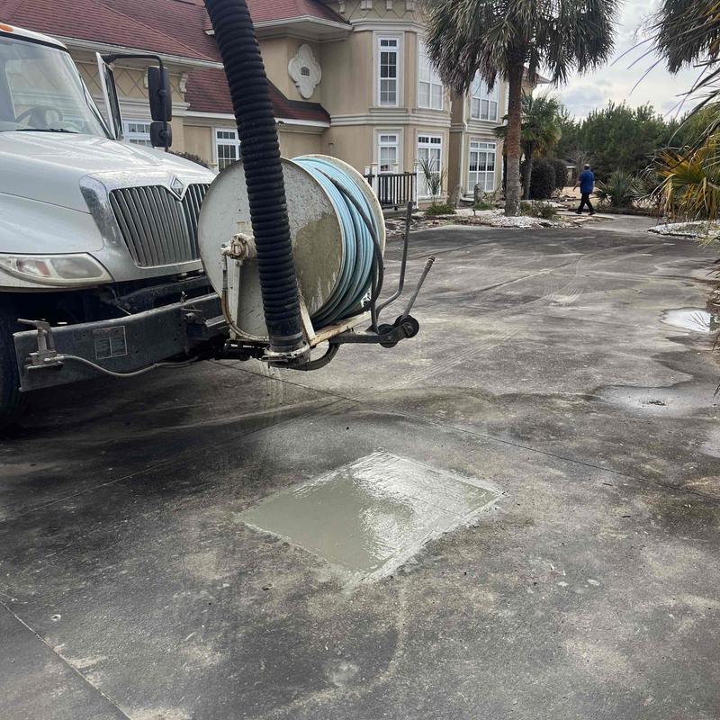 Concrete driveway patch with vac truck hose in driveway Concrete driveway patch with vac truck hose in driveway