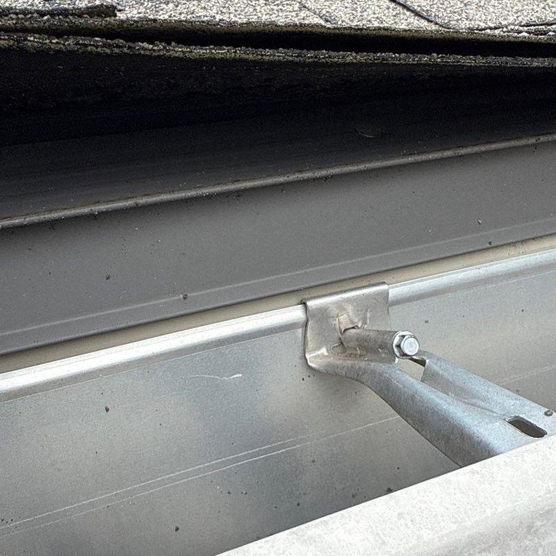 Gutter hanger bracket close-up on metal roof edge