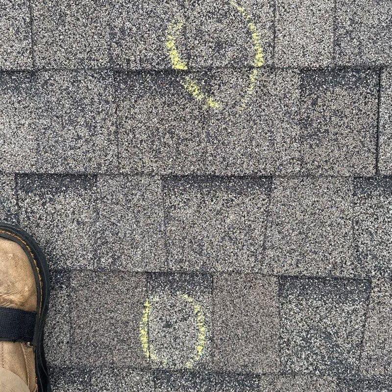 Asphalt roof shingles with hail damage marked in yellow