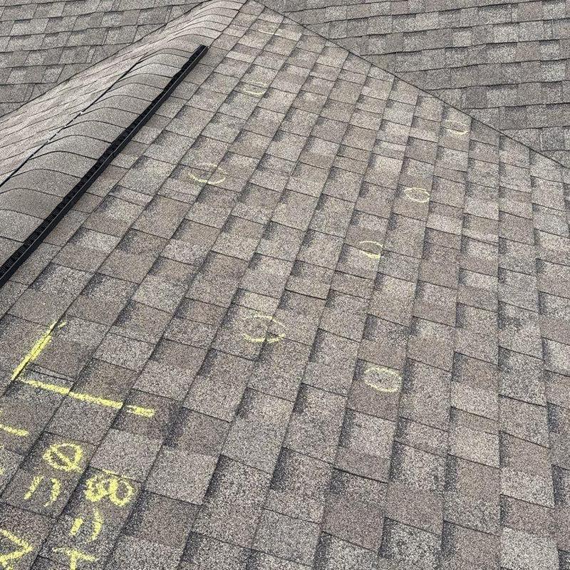 Shingle roof with hail damage marked for inspection