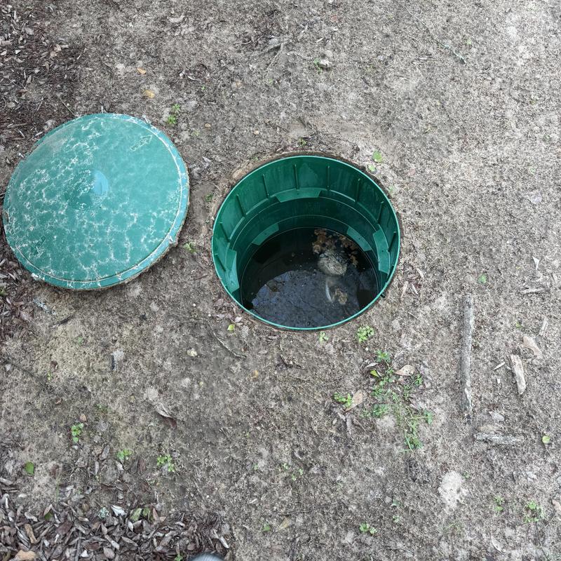 Septic system inspection with open green riser in yard