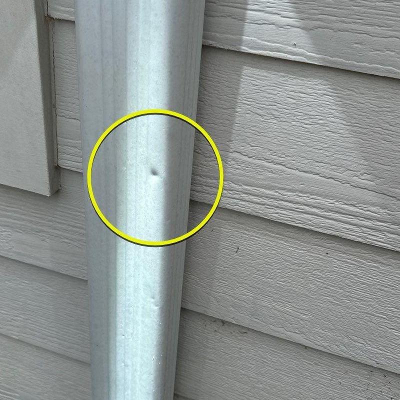 Metal downspout dent with exterior siding background