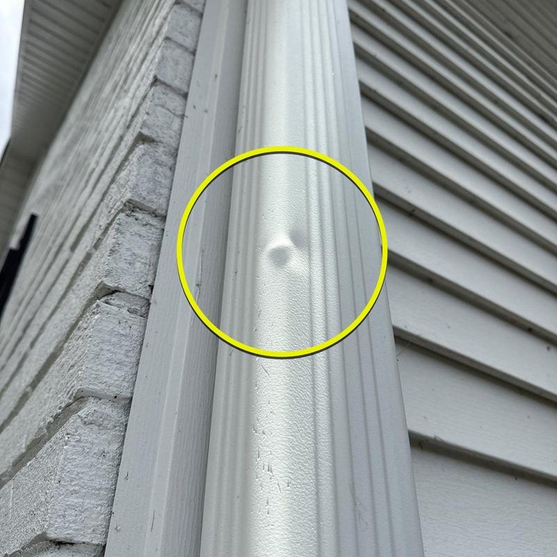 Vinyl siding dent from hail damage highlighted