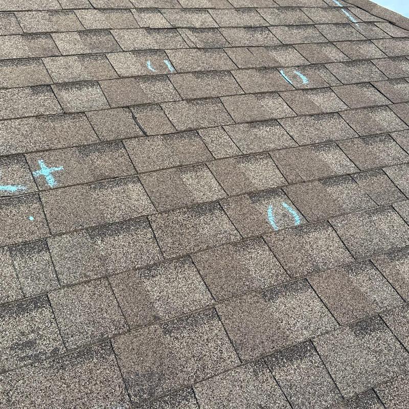 Roof shingles with hail damage marked for inspection