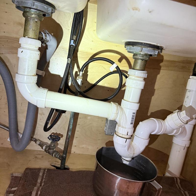 PVC drain pipes under kitchen sink with leak bucket PVC drain pipes under kitchen sink with leak bucket