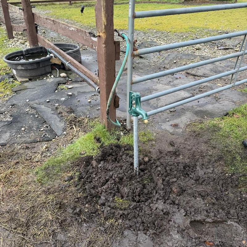 Yard hydrant installation by metal farm gate in dirt