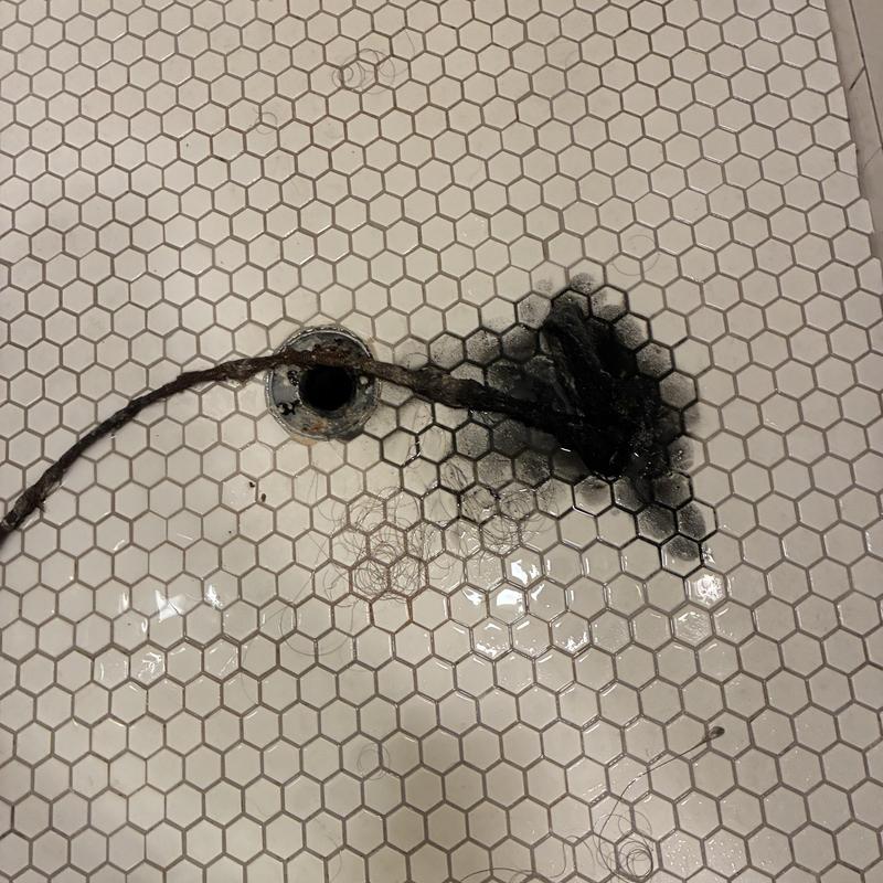 Shower drain hair clog removal on tile floor