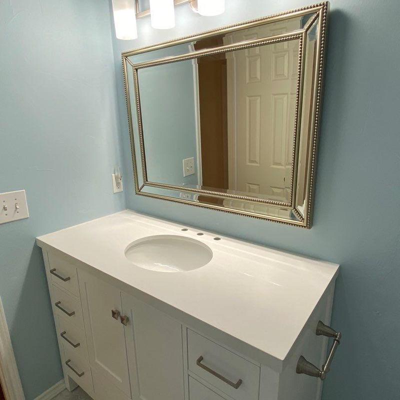 Bathroom vanity with white countertop and framed mirror Bathroom vanity with white countertop and framed mirror