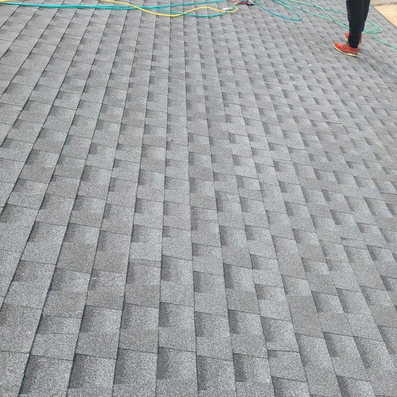 Asphalt shingle roof with hose and worker feet