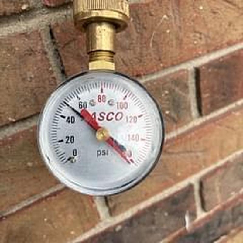 Water pressure gauge measuring PSI on brick wall