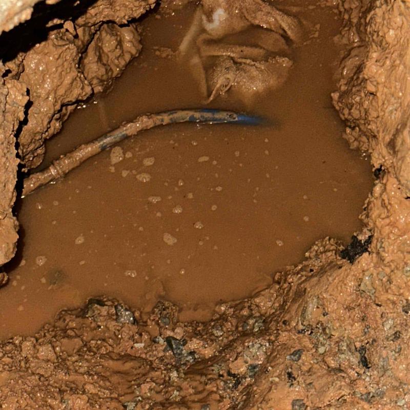 Corroded underground pipe in muddy excavated trench Corroded underground pipe in muddy excavated trench