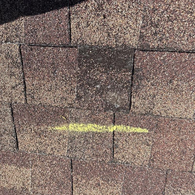 Asphalt shingles with hail damage marked in yellow