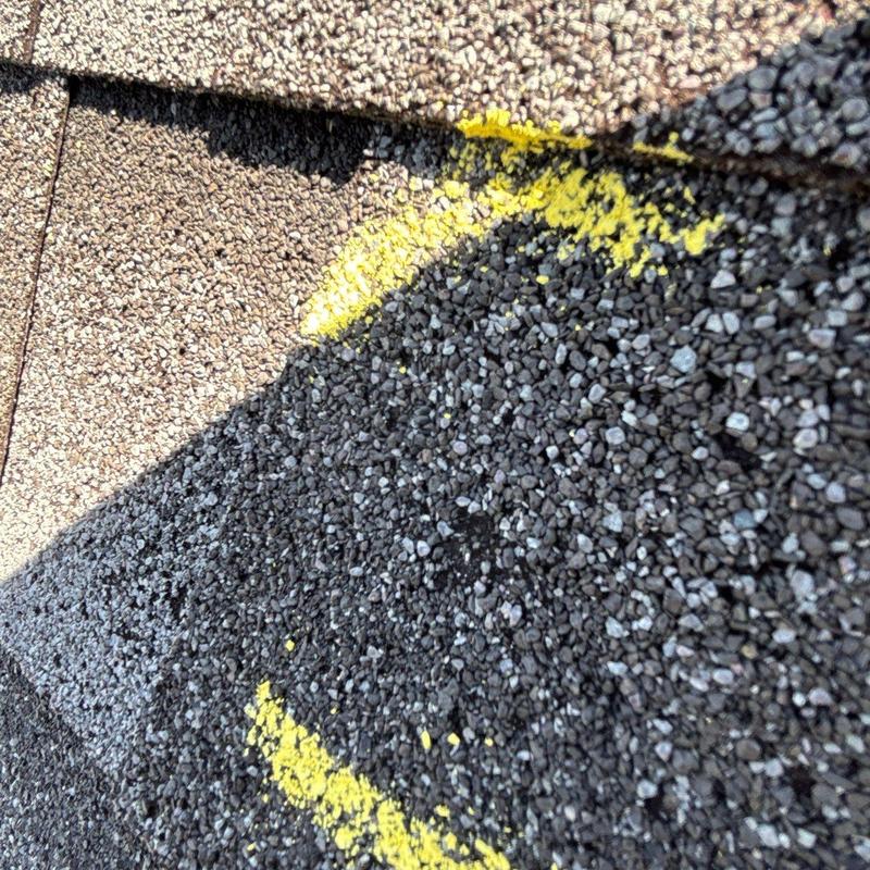 Roof shingles with hail impact marks in yellow paint