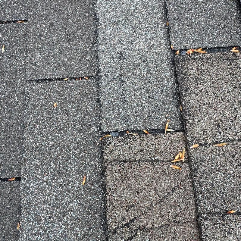 Asphalt shingle roof showing hail damage and debris