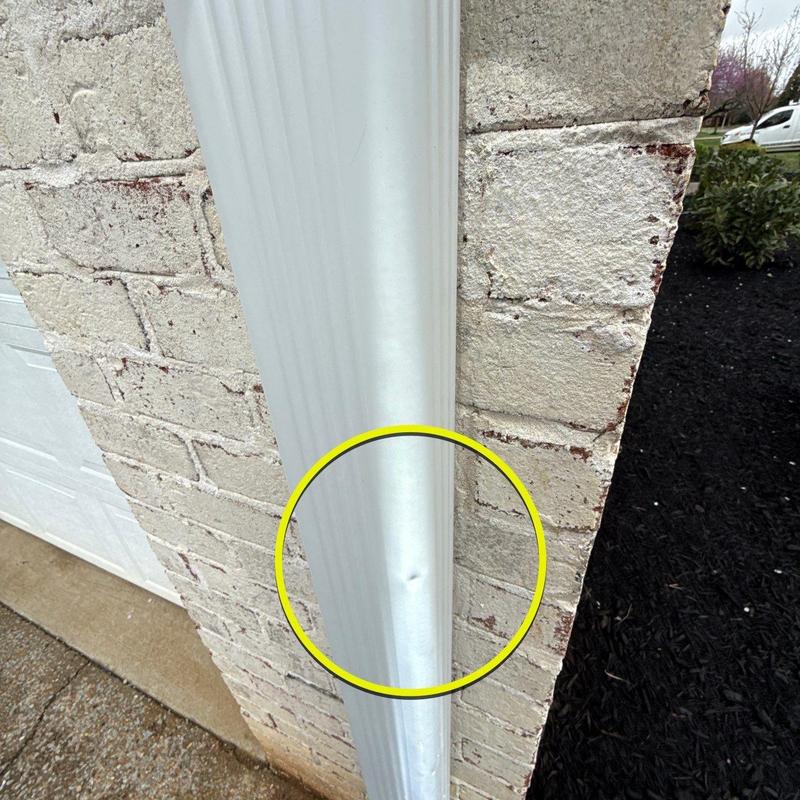 Downspout dent on exterior brick wall corner